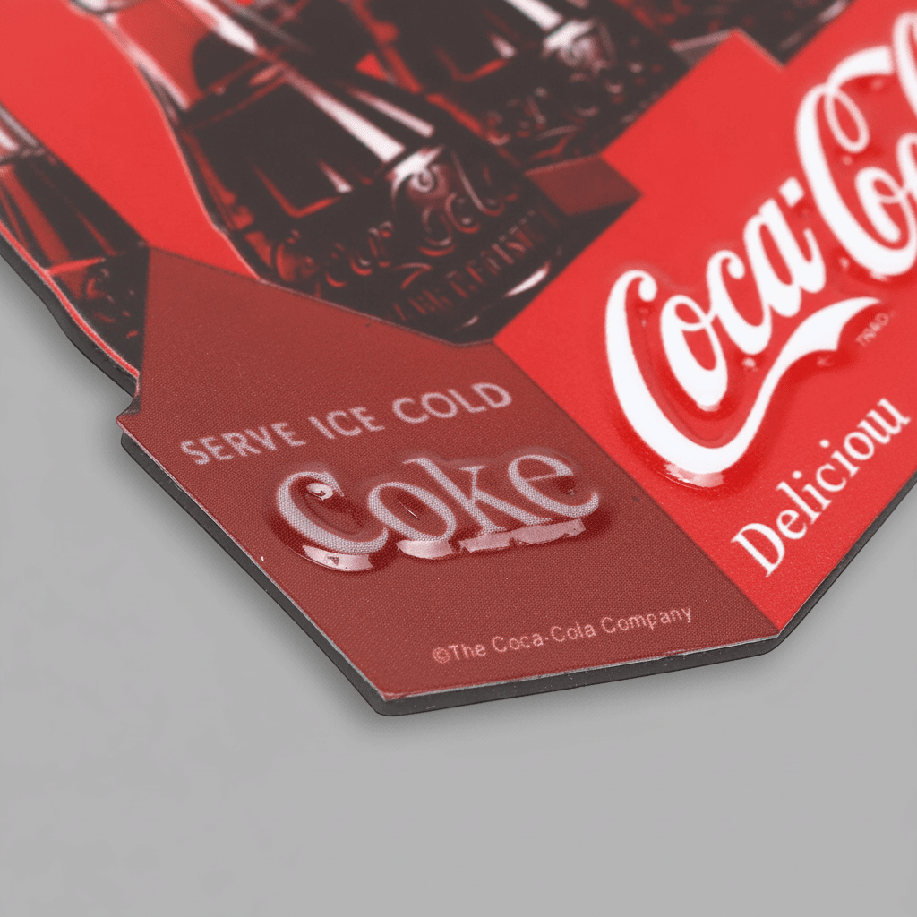Close-up of the Coca-Cola six-pack magnet showing raised Coke lettering and the red carton design.