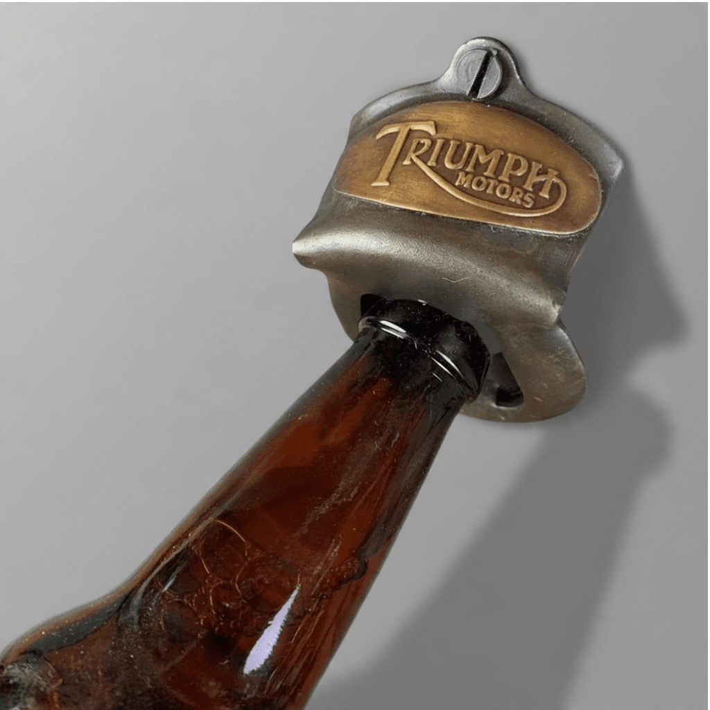 Jones Peak Triumph Motorcycles embossed metal wall bottle opener with an antiqued finish on a glass bottle neck