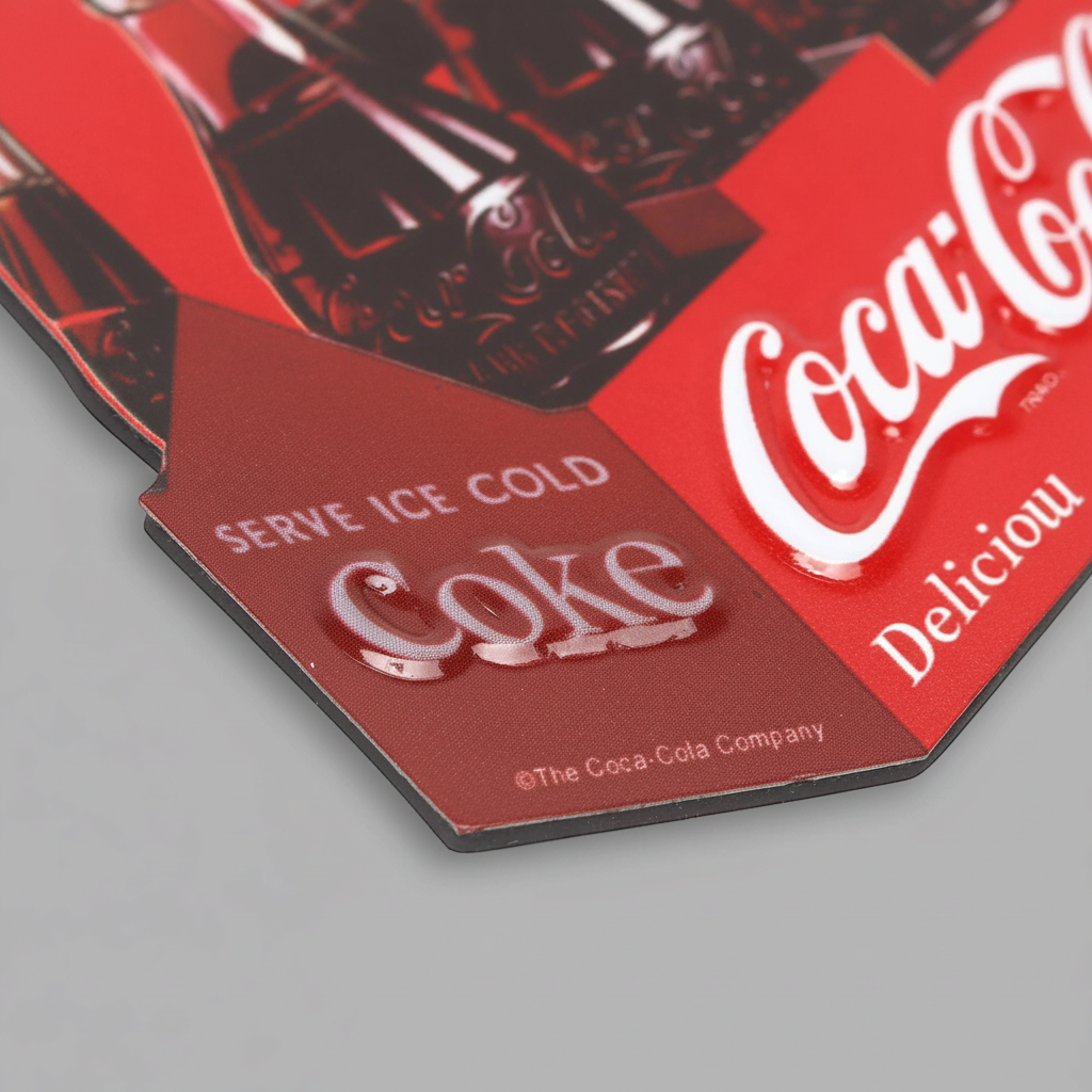 Close-up of the Coca-Cola six-pack magnet showing raised Coke lettering and the red carton design.
