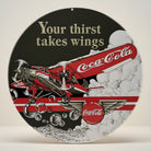 Coca-Cola AR Tri Motor round embossed metal sign with red airplane and Your Thirst Takes Wings text