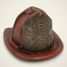 Jones Peak antique finish cast iron fireman helmet coin bank with crossed axe and ladder emblem.