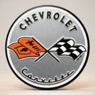 Jones Peak Chevrolet Corvette round embossed metal magnet with checkered and orange flags.