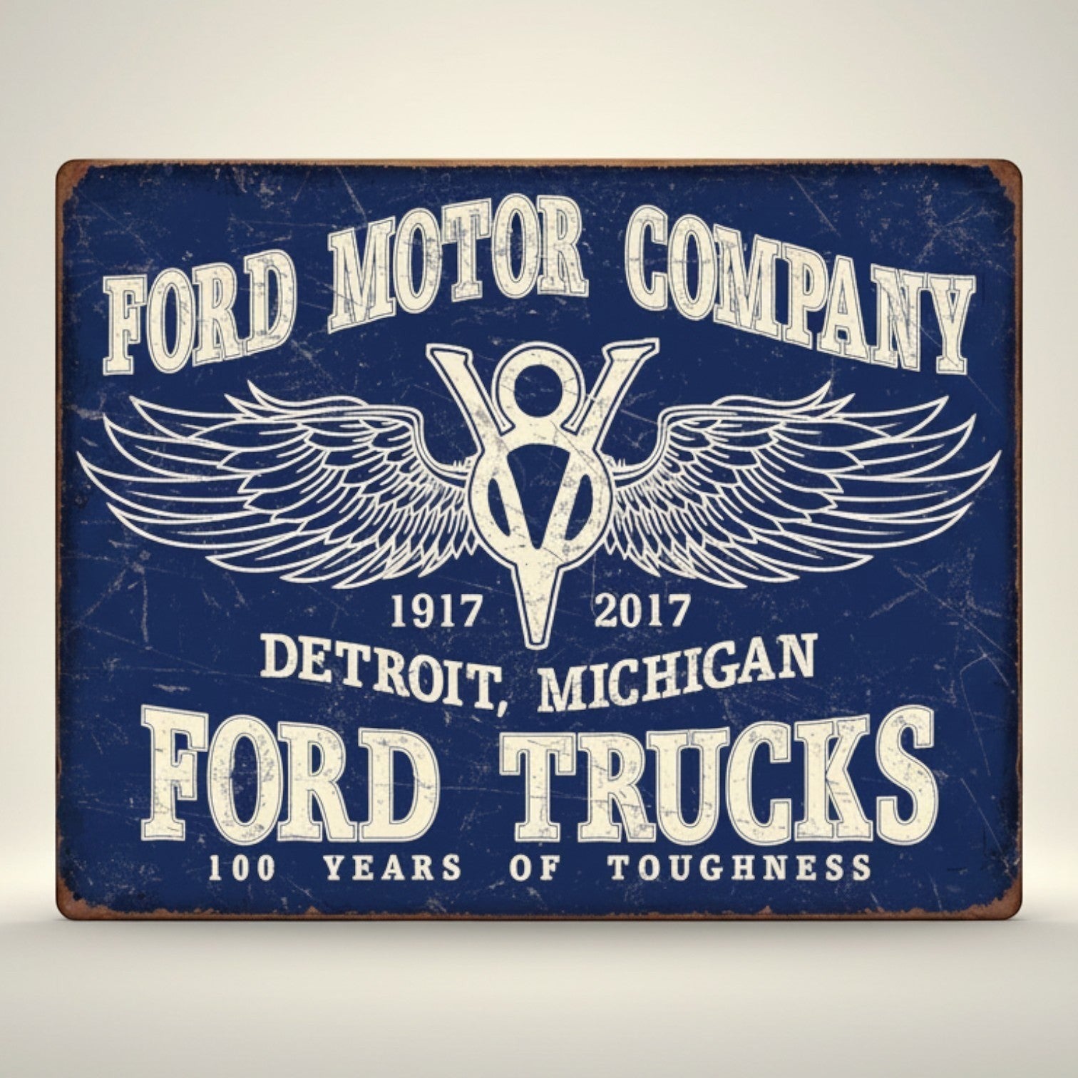 Jones Peak Ford Trucks 100 Years metal sign with Ford Motor Company logo and wings, distressed blue finish.