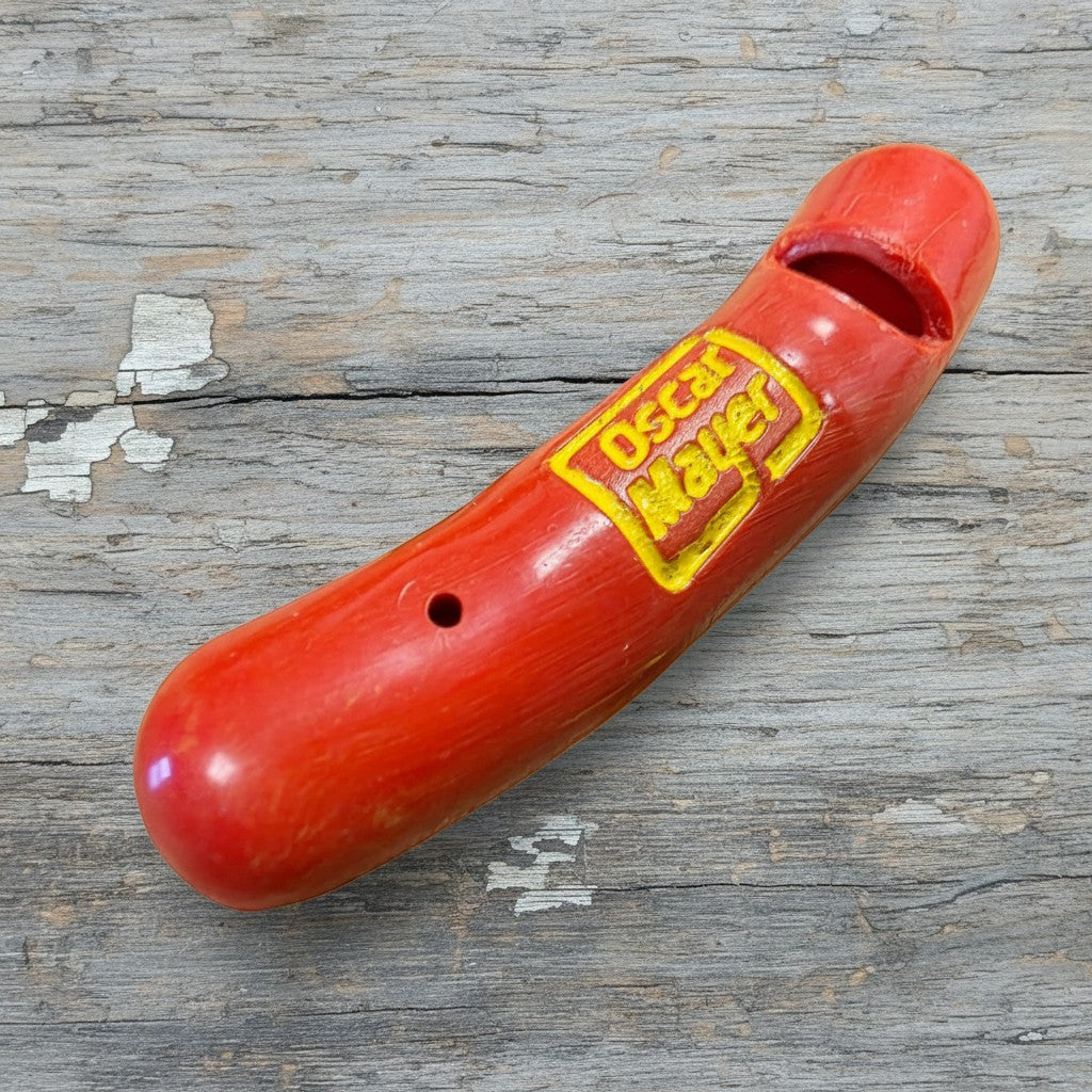 Jones Peak red plastic hot dog novelty whistle with yellow Oscar Mayer logo, 2 inches long.