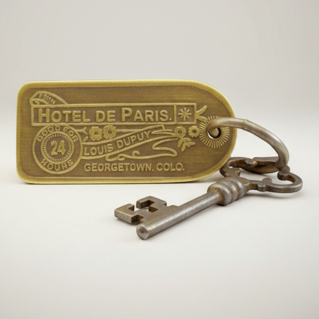Jones Peak reproduction brass hotel key tag for Hotel de Paris, Georgetown, CO. Features antique finish and decorative floral elements.