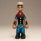 Jones Peak Sailor Cast Iron Coin Bank with hand-painted antique patina. Features blue pants, black shirt, red collar, and white hat.